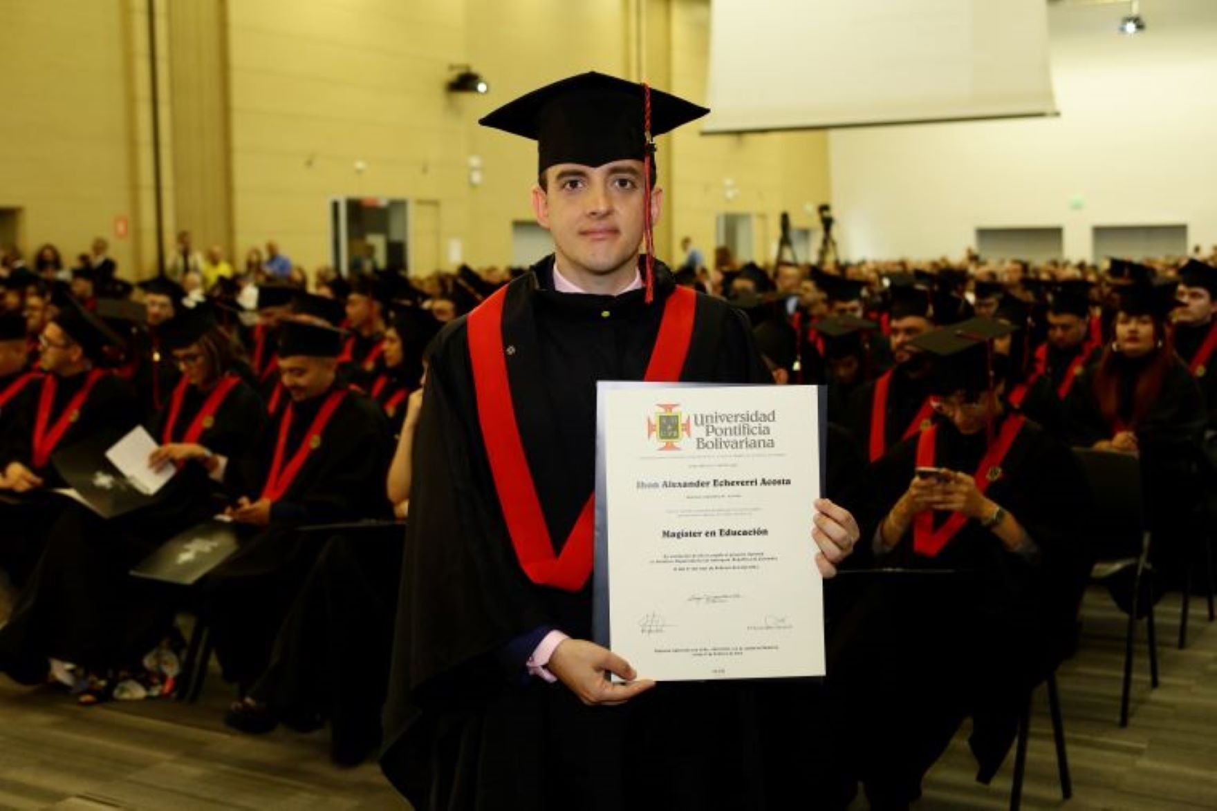 Jhon Alexander con el diploma en la graduación de Magister